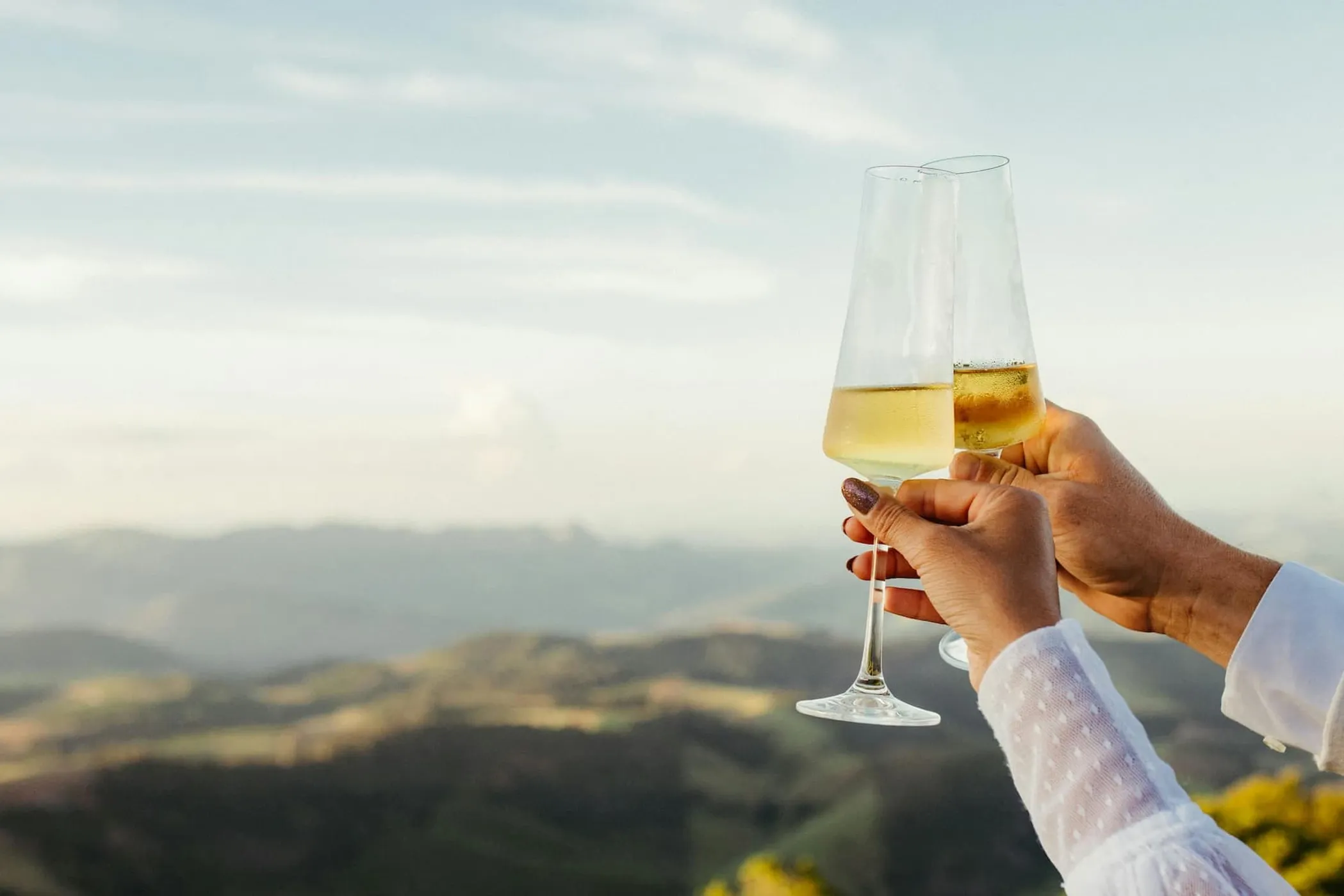 A close-up of sparkling wine glasses as a couple makes a toast.