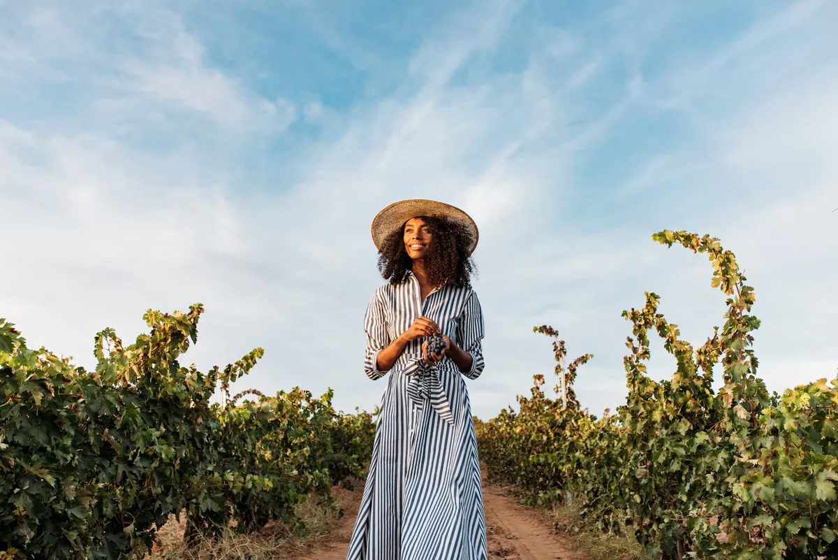 A beautiful woman walking through a vineyard.