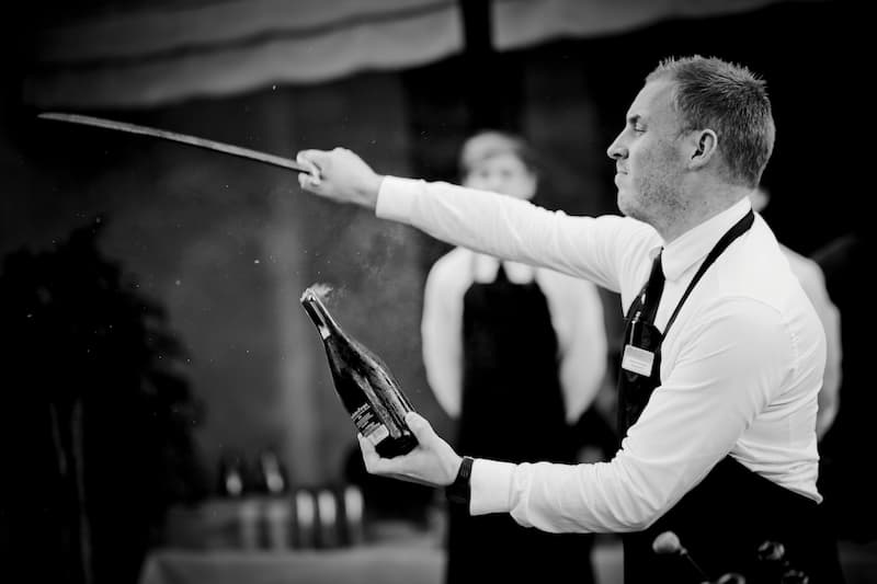 A sommelier using the sabrage method to open Champagne